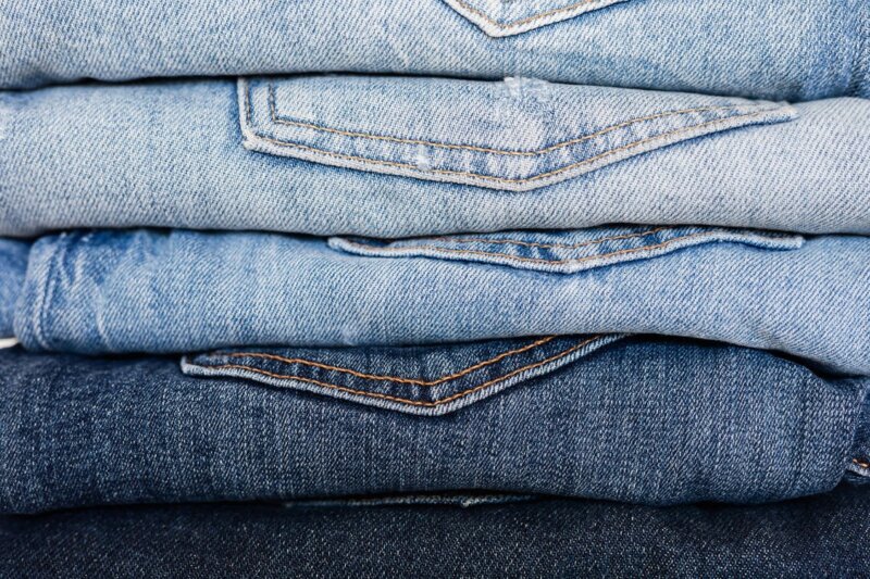 Så tvättar du jeans. På bilden ligger jeans i olika färger i en hög. 